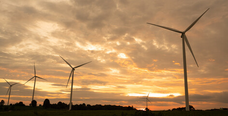 Wind turbines generate electricity in a rural area during sunset. Windmill farm on mountain with sunset sky. Wind energy, renewable energy, Green technology. © kelvn