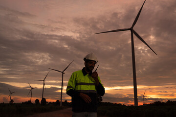 Silhouette of Maintenance engineer working in wind turbine farm at sunset. Clean energy. Alternative energy concept