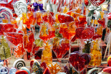 Sweet red orange lollipops cockerel figurines at Christmas market