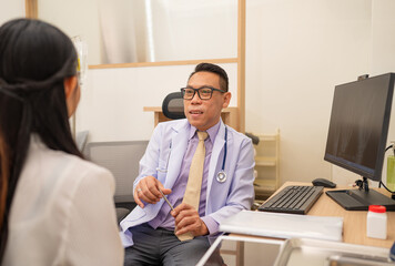Fototapeta premium Mature male doctor explain to the woman patient the result of x-ray that show fracture of her calcaneus. Doctor Showing X-ray To Patient On Computer Screen.