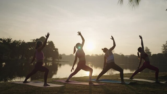 Group of Asian women in sportswear stretching and relax during yoga class in city park in Sunlight,Outdoor Activity and Sports Apparel Concept.