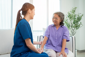 Obraz premium Asian young nurse taking care and talking mature female patient sitting on sofa in hospital. Healthcare concept.