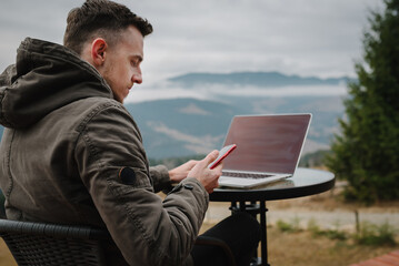 Man work on laptop sitting by table with great view mountains. Empty screen laptop. Concept remote...