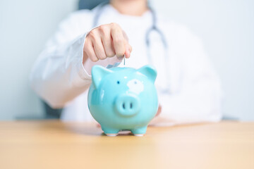 Doctor holding piggy bank and putting coin. and Healthcare cost, Money Saving, Health Insurance, Medical, Donation and Financial concepts - obrazy, fototapety, plakaty