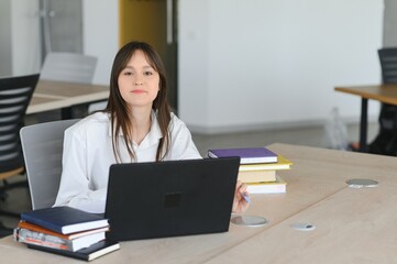 A cute schoolgirl is sitting at a desk at school. The concept of schooling.