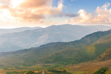 Naklejka premium scenic rustic landscape with green hills and farms in a mountain valley during colorful cloudy sunset