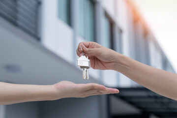 Real estate agent delivering keys house, Hands pass a house key as a symbol of real estate and...