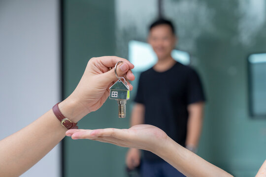 Real estate agent delivering keys house, Hands pass a house key as a symbol of real estate and house buying.