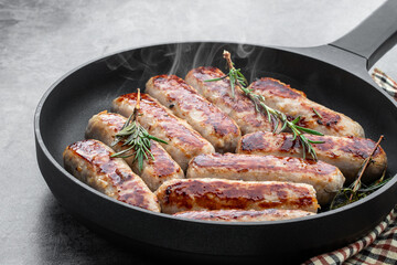 Delicious pork sausages in a frying pan on gray background