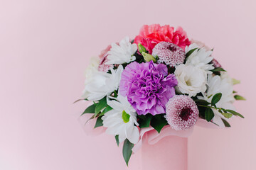 Beautiful bouquet of pink. violet and white flowers on a pink pastel background.