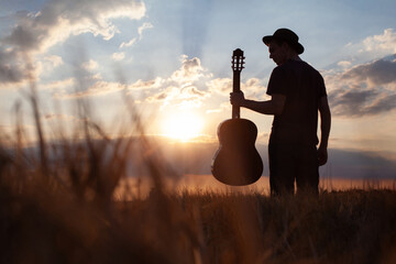 silhouette of man with guitar and hat, summer music festival - obrazy, fototapety, plakaty