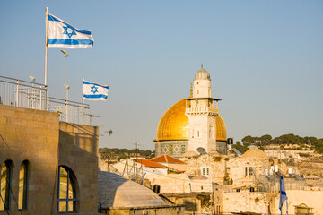The Al-Aqsa mosque, Qibli Mosque or Qibli Chapel, المصلى القبلي, on the Temple Mount, old town of Jerusalem. Golden dome and ancient stone buildings. Israeli flags seen before blue sky