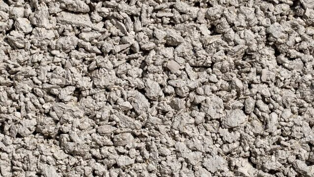 Background small fractions of crushed stone with sand frozen in cement mortar, moving sideways, close-up macro, top view
