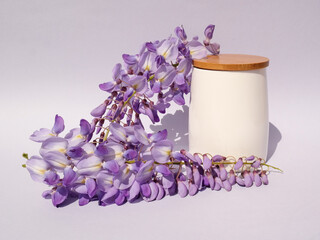 White bamboo cup with wisteria flowers on gradient white and gray background. Natural minimal concept. Creative spring idea. Wisteria decoration.