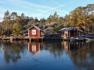 Fototapeta na wymiar Picturesque cabins and a boat on the shore of a tranquil lake with trees in the background