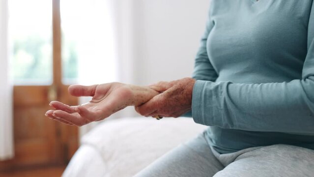 Hand, wrist pain or arthritis with a senior on the bed in a home for recovery from injury closeup. Anatomy, osteoporosis or fibromyalgia with an elderly person in the bedroom of an apartment