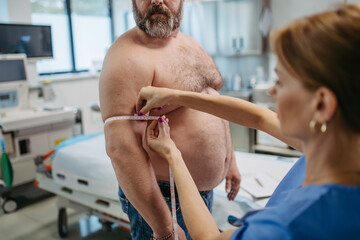 Female doctor measuring arm circumference of overweight patient using tape measure. Obesity...