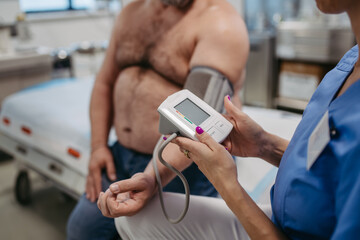 Female doctor measuring blood pressure, examining hypertension, using blood pressure monitor....