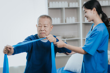 Obraz premium Asian female doctor or nurse exercising with elderly man at hospital