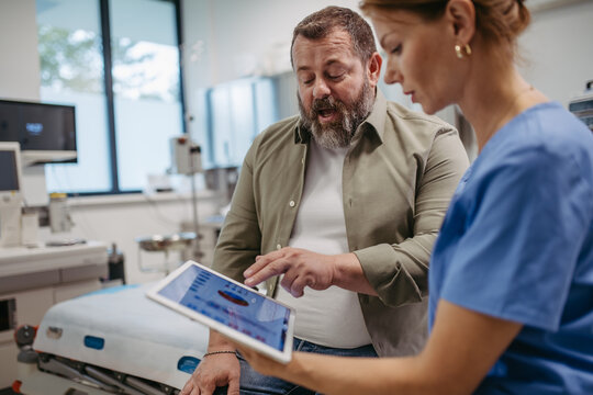 Female doctor consulting with overweight patient, discussing test result in doctor office. Obesity affecting middle-aged men's health. Concept of health risks of overwight and obesity.