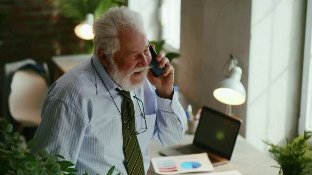 The general director, the head of the company, relaxes in the office, talking on the phone, smiling