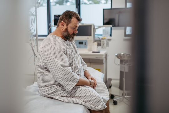 Overweight patient in hospital gown waiting for medical examination, test results in hospital, feeling anxious. Patient feeling dizzy, have vertigo and intense pain.
