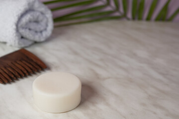 Obraz na płótnie Canvas Sustainable solid shampoo bar, towel and wooden comb on a light background. Eco friendly hair care. Plastic free, zero waste living, low water ingredients. Minimalistic. Side view, copy space.