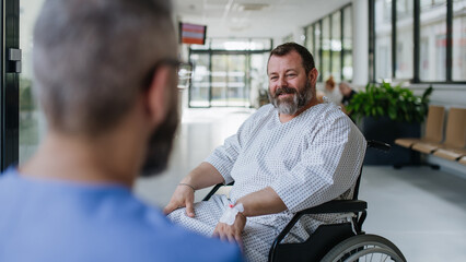 Close up of supportive doctor talking with worried overweight patient in wheelchair. Illnesses and diseases in middle-aged men's health. Compassionate physician supporting stressed patient. Concept of