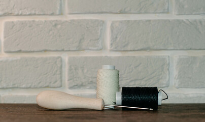 Shoe awl and skeins with white and black threads.