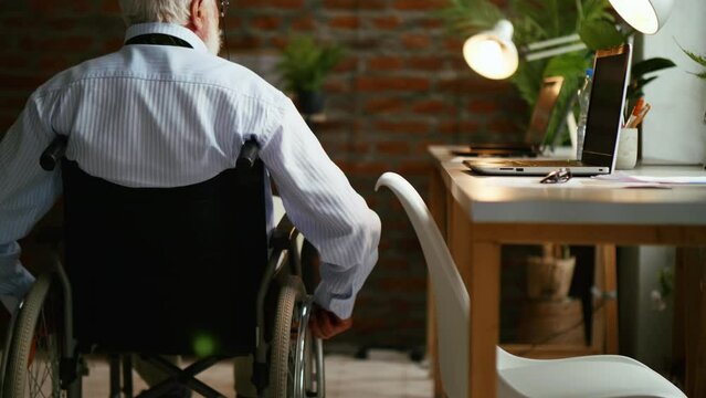 Old person with a disability businessman is riding a wheelchair in the office at work