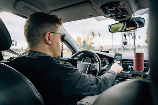 A man uses a smartphone installed in the holder while driving a car