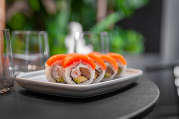 Sushi roll with salmon, shrimp, avocado and cream cheese on a plate close-up