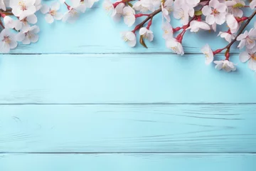  Pink cherry blossom branch and flower placed on blue wooden table top background in Spring with space for text. Spring seasonal concept. © Joyce