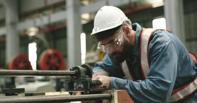 team of technician workers is using tools to service machine produces sheet metal in factory. Engineers are inspecting machines and repairing them profession. Wear safety helmet to prevent during work