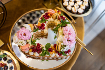 Heart-shaped cake is luxuriously decorated with berries, mint leaves, fruits, meringues, and cream .
