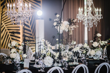 Luxury wedding reception. Trendy decor large chandelier for a birthday party. Table setting, setup....