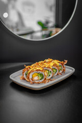 Sushi roll with tuna flakes, tempura shrimp, mango and cucumber on a plate