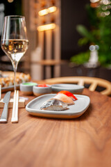 Nigiri set: mackerel, sea bass, salmon on a plate on a table in a sushi bar