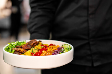 chef or waiter hold plate of Cobb salad