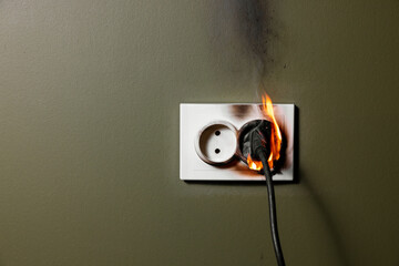 burning wall electrical socket with plugged appliance cable from short circuit in house. concept of...