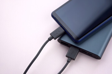 Power bank for charging mobile devices. Black smart phone charger with power bank.