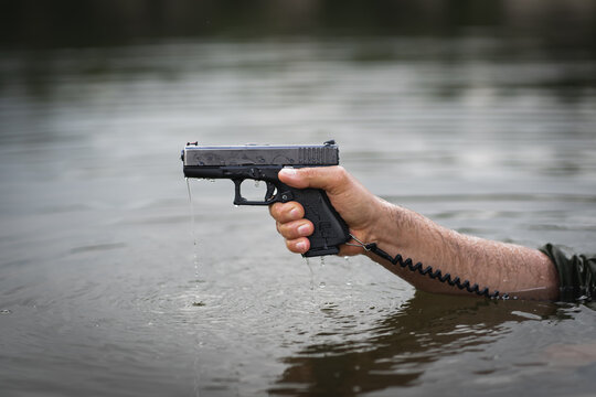 Baltic States, August 25, 2023.  Wet Glock 19 pistol in male hands.