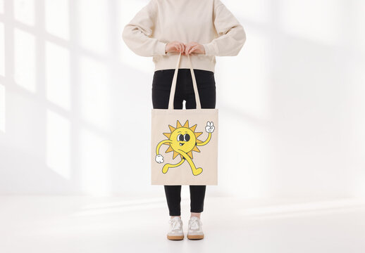 Mockup of woman holding customizable tote bag, low section