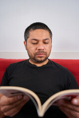 Deep in Thought: Man Reading on Sofa