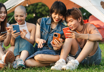 Image of a group of young Asian people laughing together and using their phones