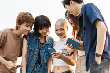 Image of a group of young Asian people laughing together and using their phones