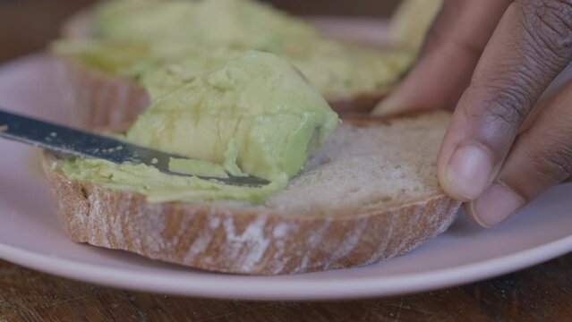 Cooking sandwich with avocado. Toast with avocado. Avo on toast. Spreading Mashed Avocado On Toast. Healthy Vegan Breakfast. Fresh Avocado toast close up. Healthy vegan food concept.