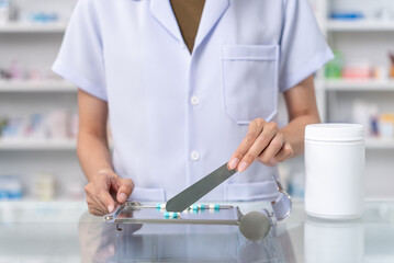 Close up of female pharmacist counting and arrange pills on qualified stainless counting tray with spatula in pharmacy. Pharmacist prepare medication in stainless tray by prescription at drugstore.