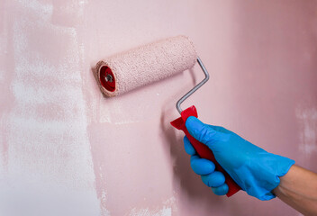 Painting a wall with a paint roller close-up