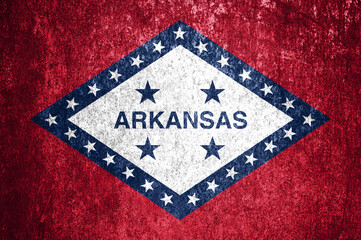 Close-up of the grunge Arkansas state flag. Dirty Arkansas state flag on a metal surface.